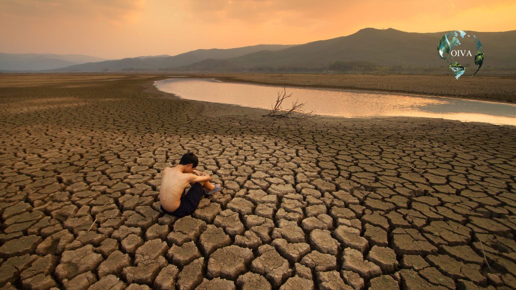 Persona sentada sobre un terreno agrietado junto a un embalse casi seco, que ilustra la crisis hídrica y climática contemporánea.